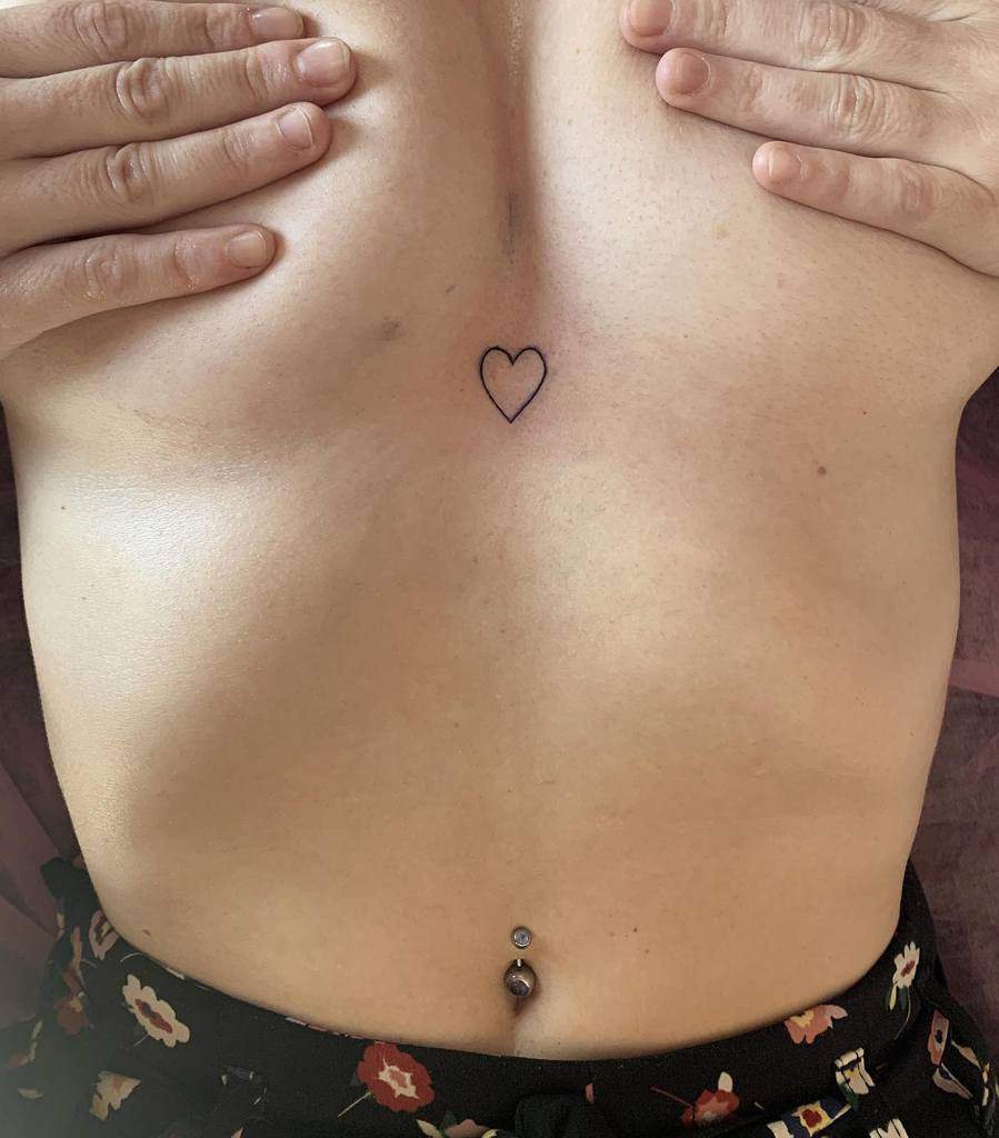 Woman with a small heart outline tattoo on her chest 