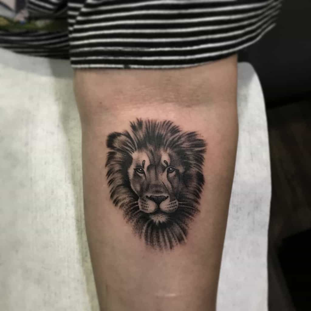 A small lion tattoo graces the inner forearm, exuding strength and elegance in every detail