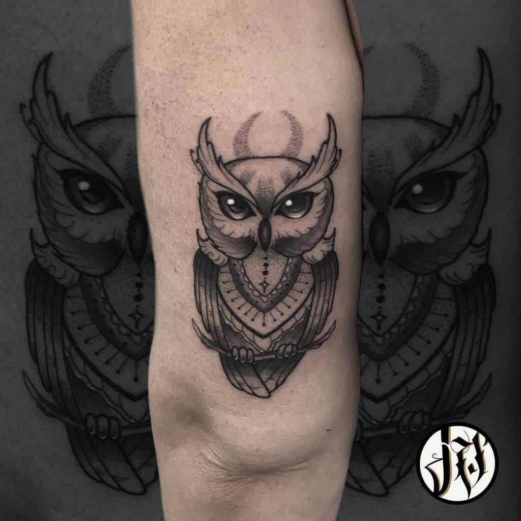 An arm tattoo featuring a stylized owl, its detailed wings spread majestically, adorned with intricate geometric patterns that enhance the enigmatic allure of this nocturnal creature