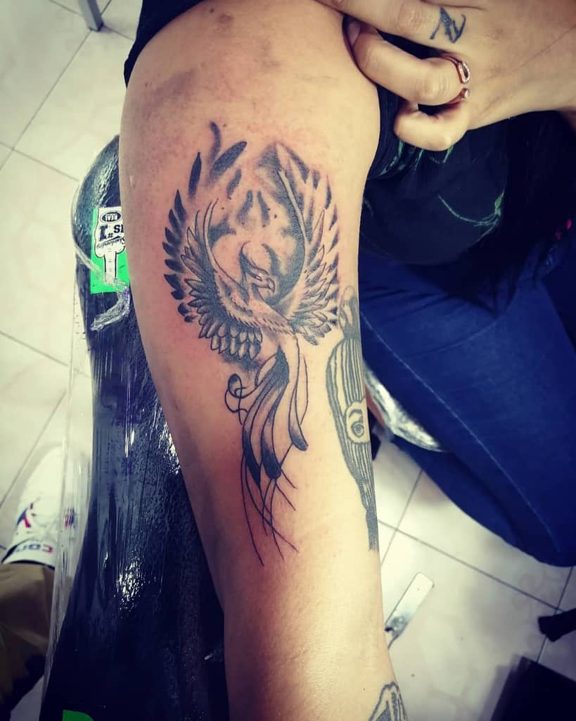 A mesmerizing tattoo of a phoenix unfurls across the person's arm, its fiery wings symbolizing rebirth and resilience in vibrant detail