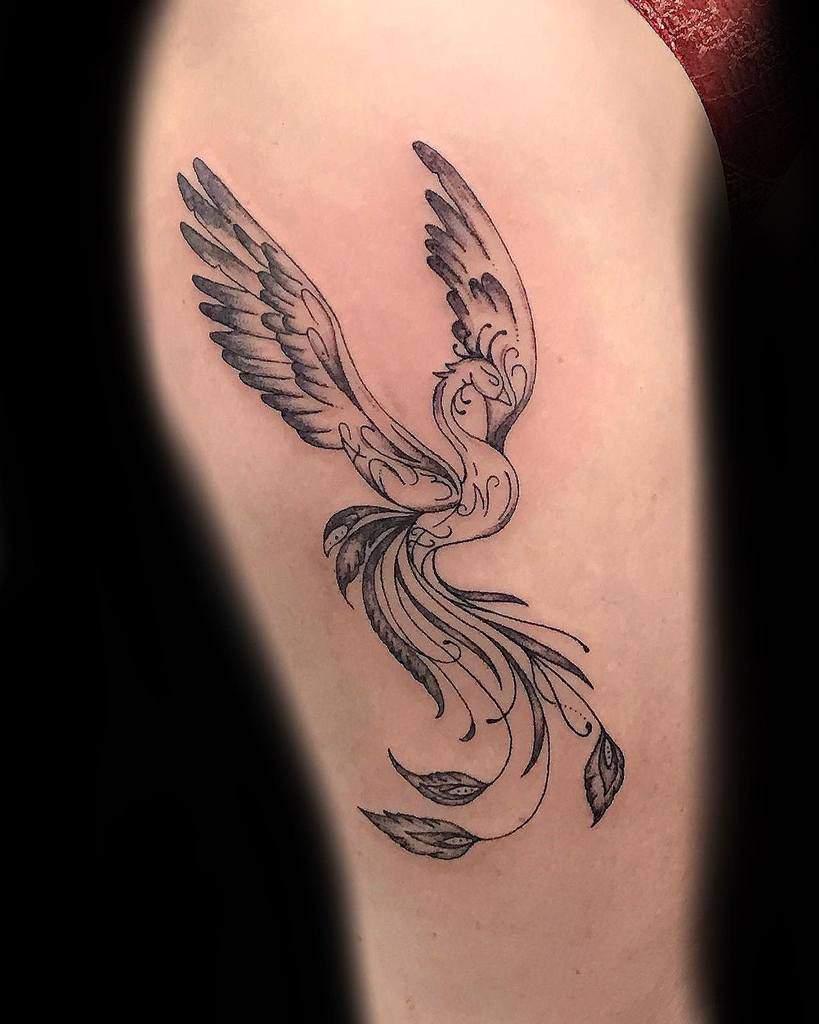 Tattoo of a stylized phoenix with flowing tail and wings