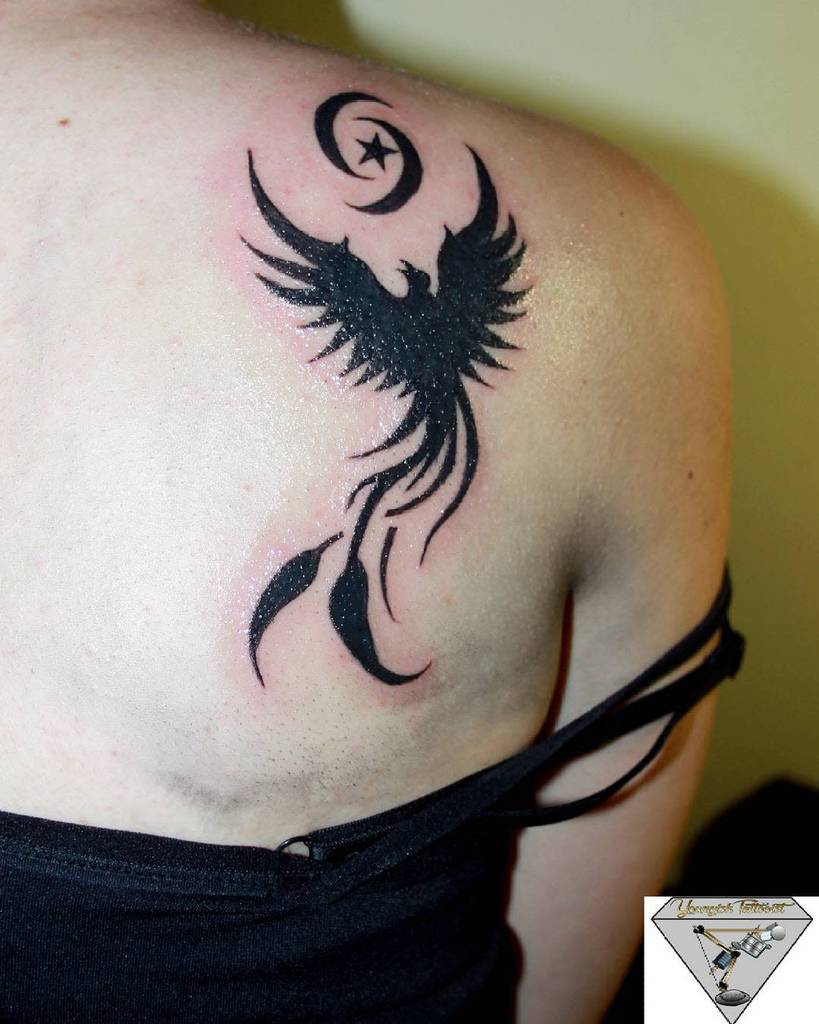 A stunning phoenix rises from the ashes, elegantly intertwined with a celestial crescent moon and star on an upper back