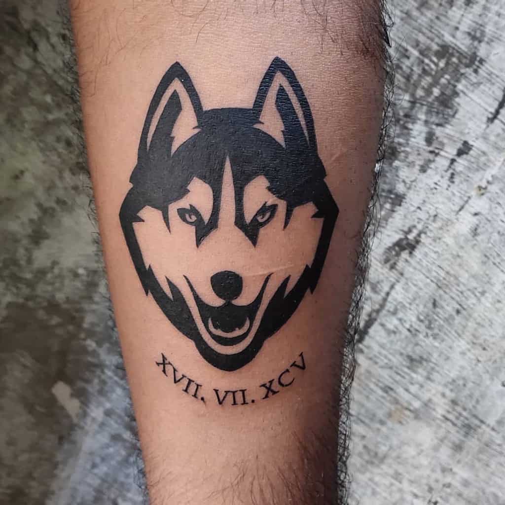 A tattoo of a majestic wolf's head with the Roman numerals XVII.VII.XCV elegantly etched beneath it
