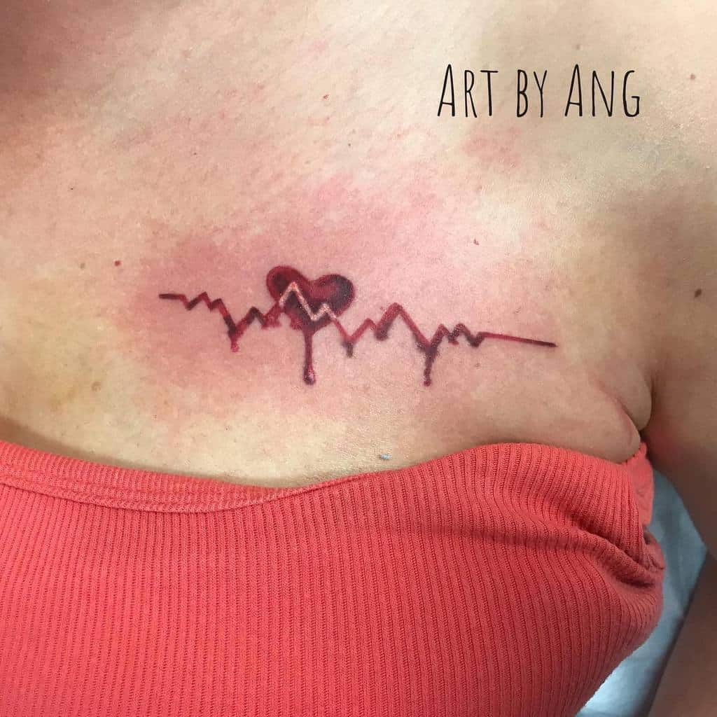 A red heart tattoo with EKG lines and a paintbrush effect beneath, located on the chest, gives the impression of a bleeding heart