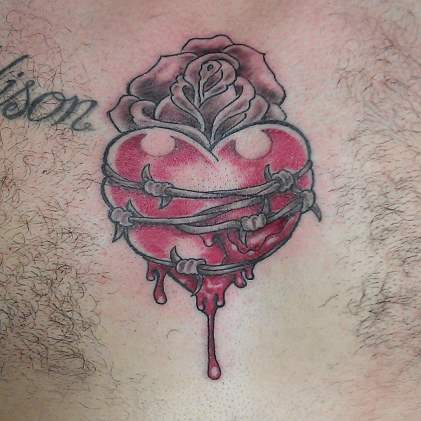 Tattoo of a bleeding heart wrapped in barbed wire with a rose on top and blood dripping