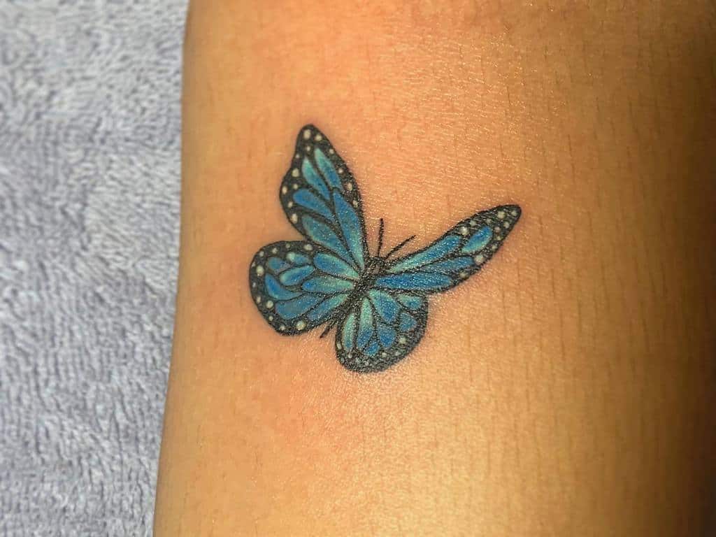 A small delicate blue butterfly tattoo