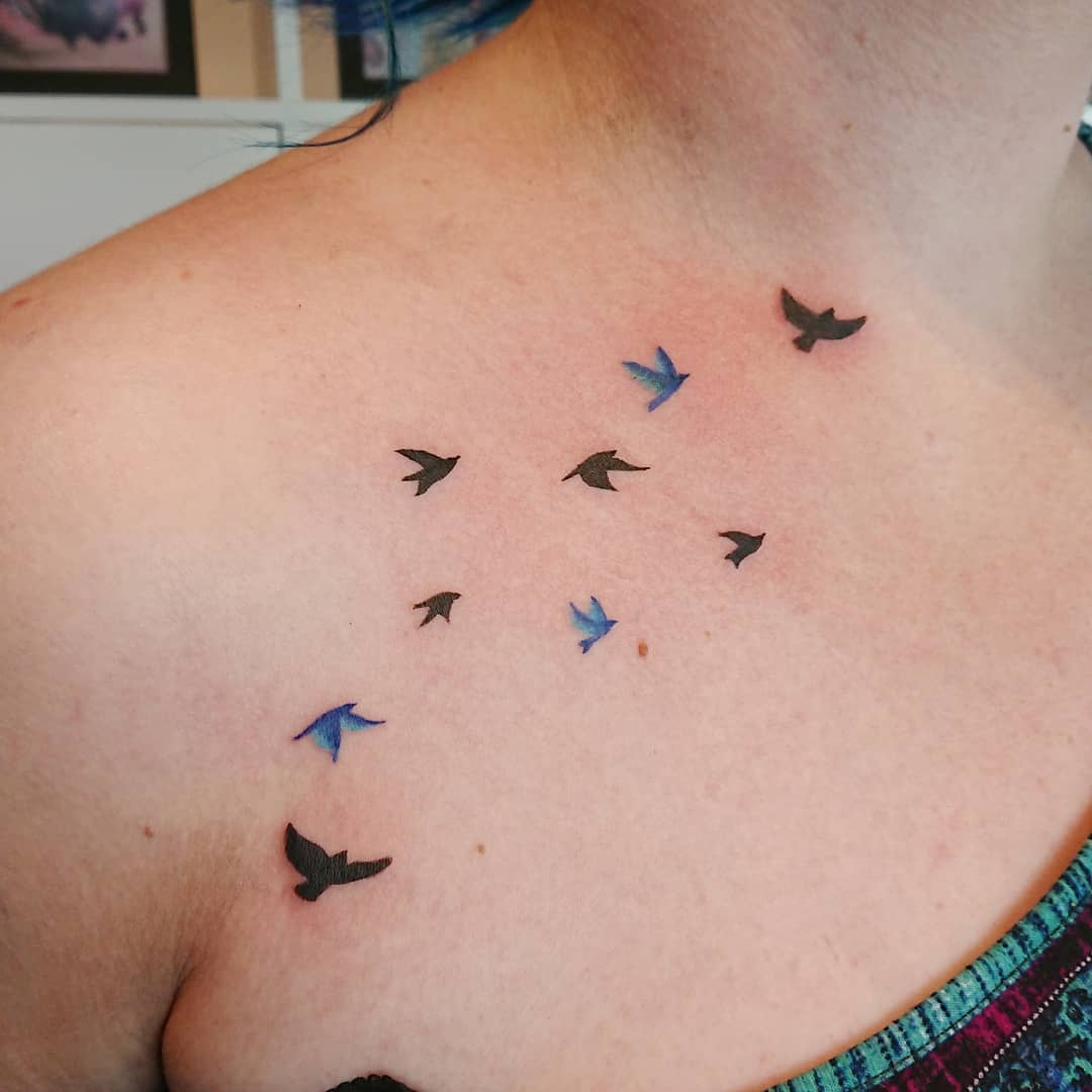 Shoulder tattoo of flying swallows in black and blue ink