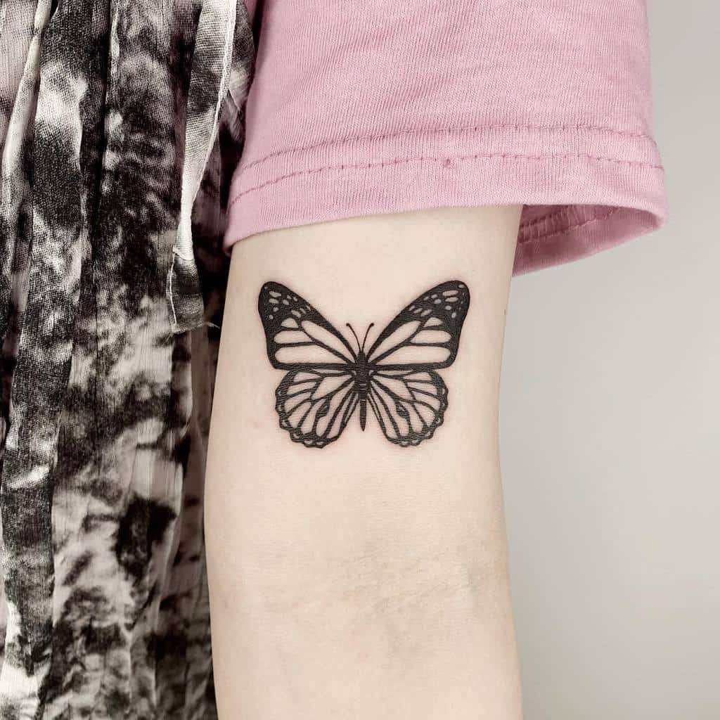 A stunning black butterfly tattoo graces a person's arm