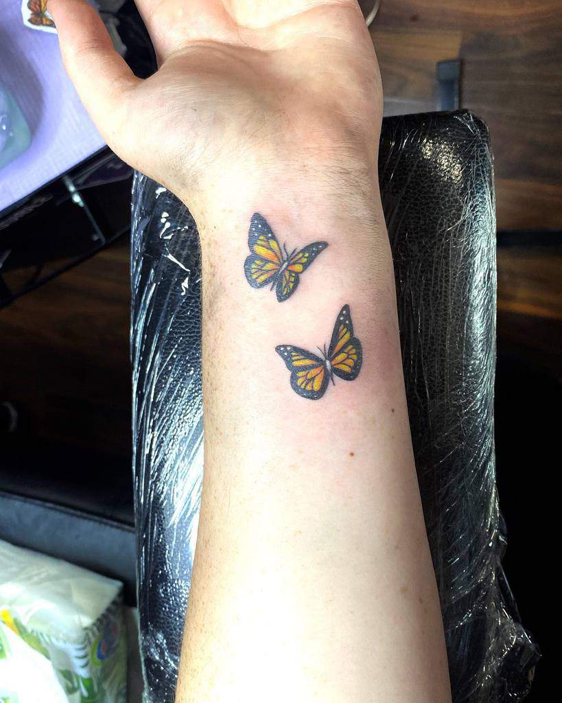 Two butterfly tattoos on a wrist, one above the other