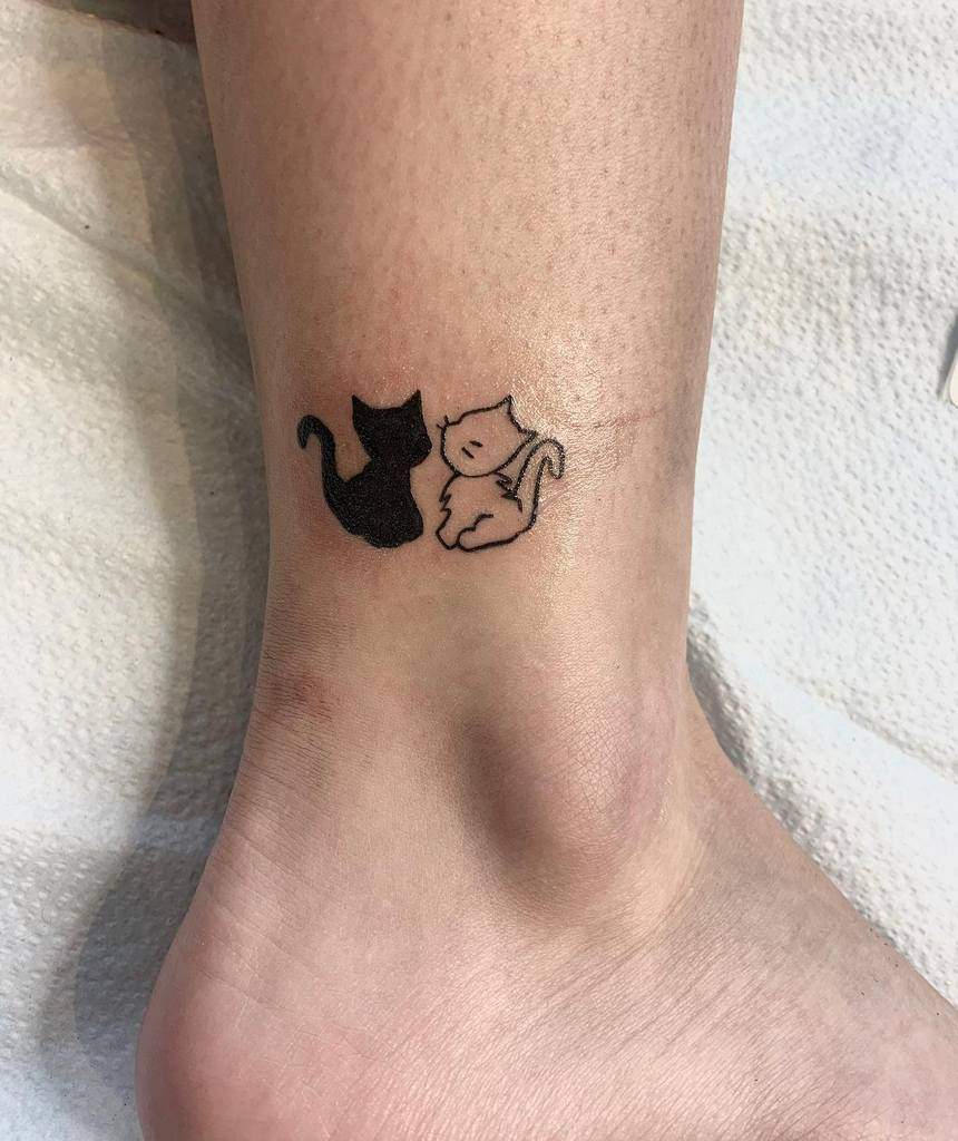 Two cat tattoos on an ankle, one black and one outlined