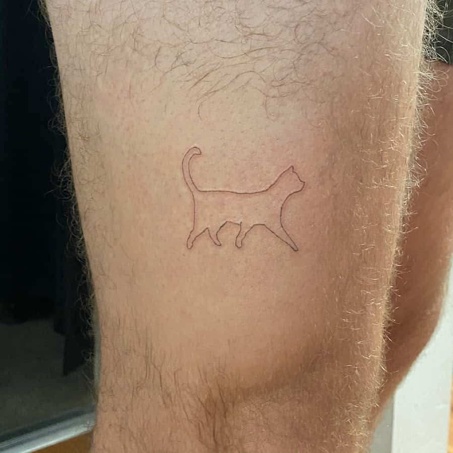 Outline tattoo of a playful cat above the knee