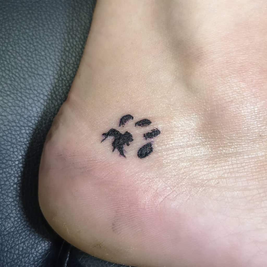 Black cat paw print tattoo on the side of a person's foot
