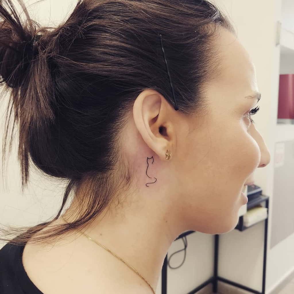 Woman with a cat outline tattoo behind her ear
