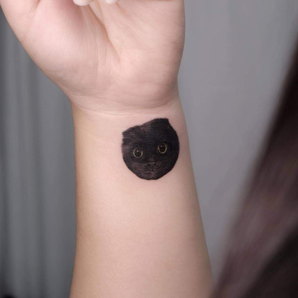 Black cat face tattoo on a wrist