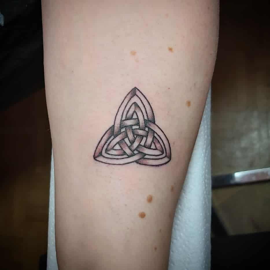 Celtic knot tattoo with a triangular design on forearm, showing interwoven bands in a grayscale style
