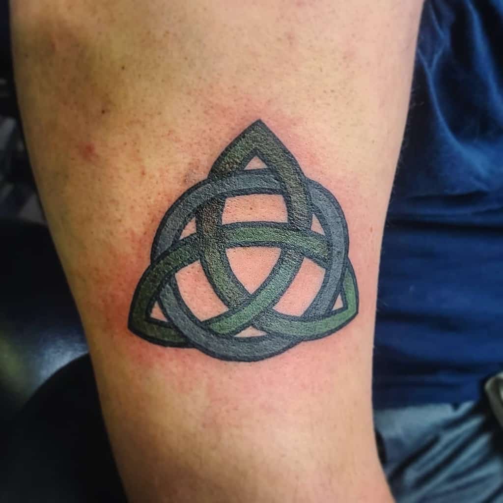 A Celtic knot tattoo on an arm, featuring a bold symmetrical design with interwoven loops