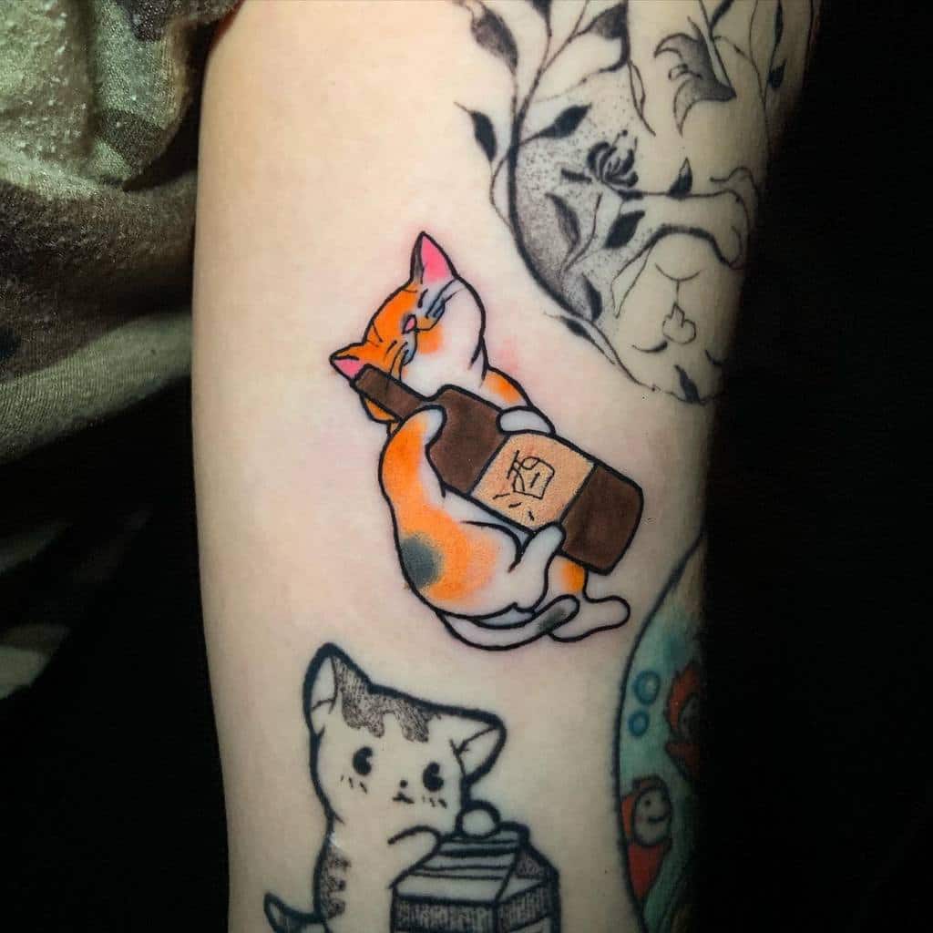 Tattoo of a cat hugging a bottle with other cat tattoos nearby