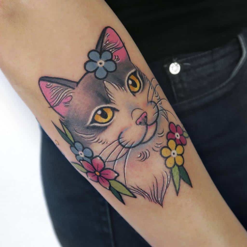 Tattoo of a cat's face adorned with colorful flowers on an arm