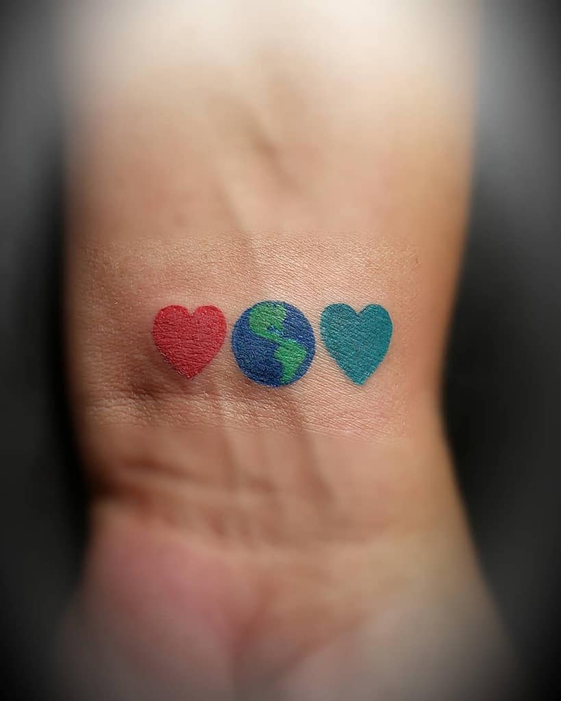 Tattoo of a red heart, blue and green Earth, and teal heart on skin