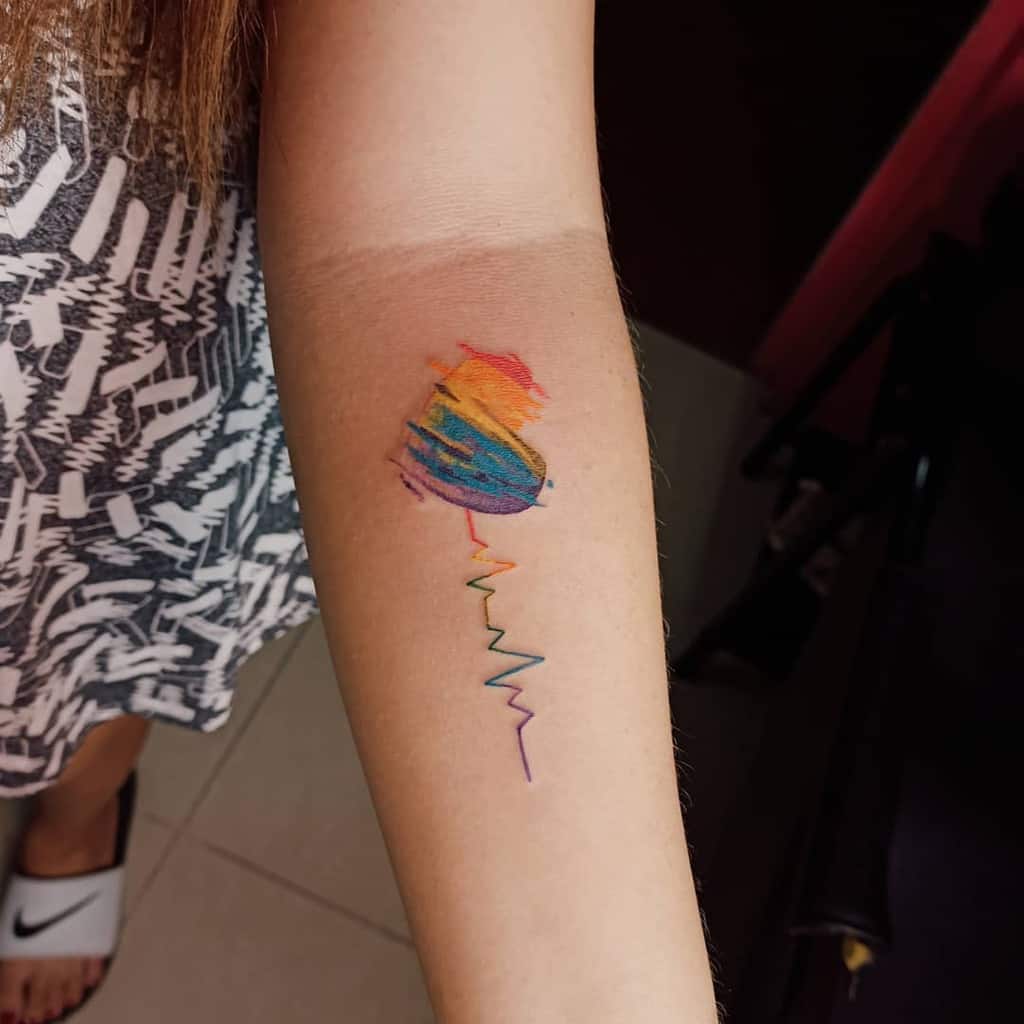 Tattoo of a colorful hot air balloon with a heartbeat line on an arm