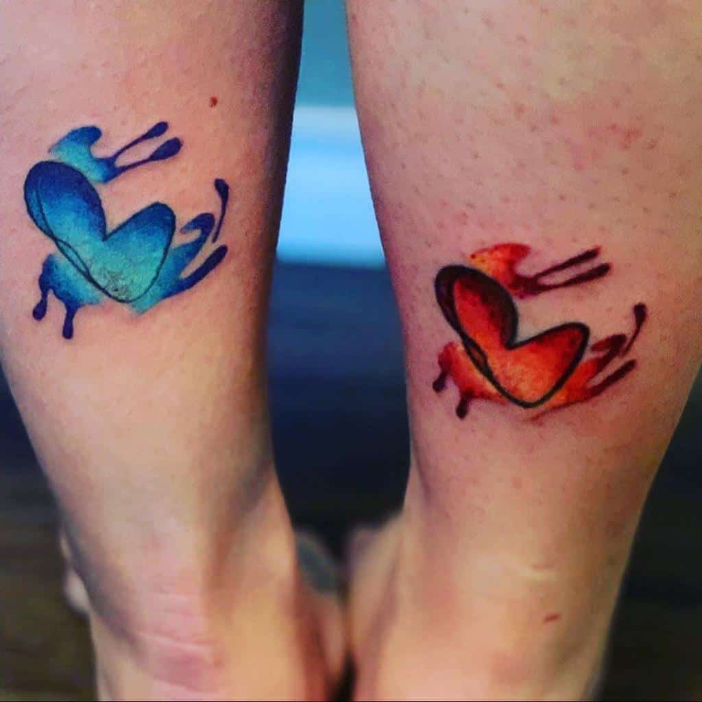 Two calves with abstract heart tattoos: one blue, one red