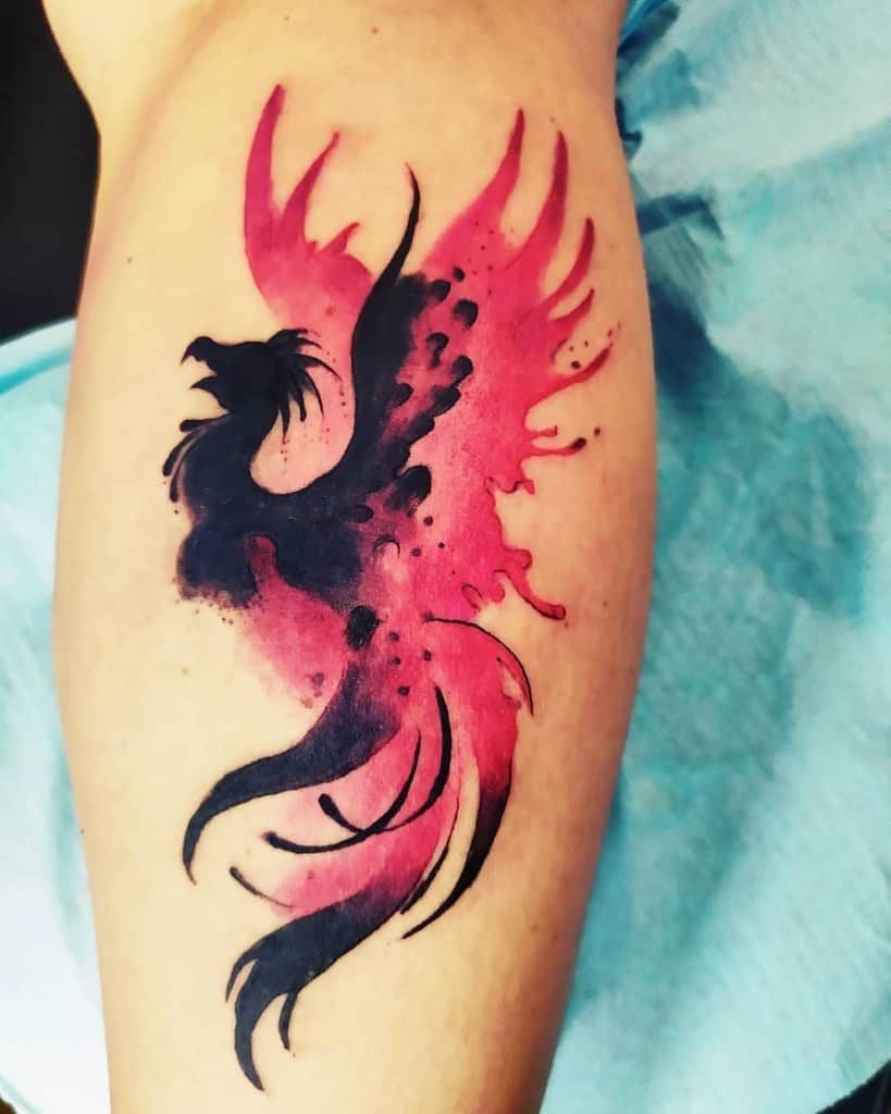 A striking phoenix tattoo, intricately crafted in bold black and vibrant red ink, graces the forearm