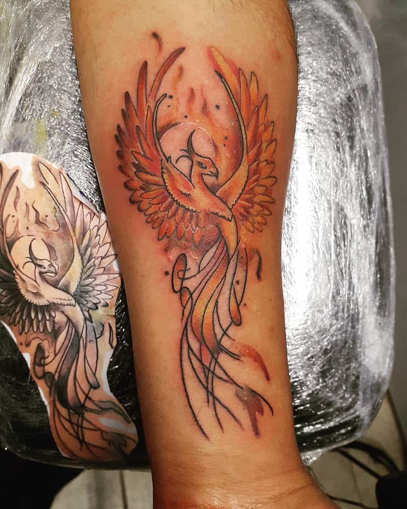 A vibrant tattoo of a fiery phoenix with outstretched wings adorns the forearm