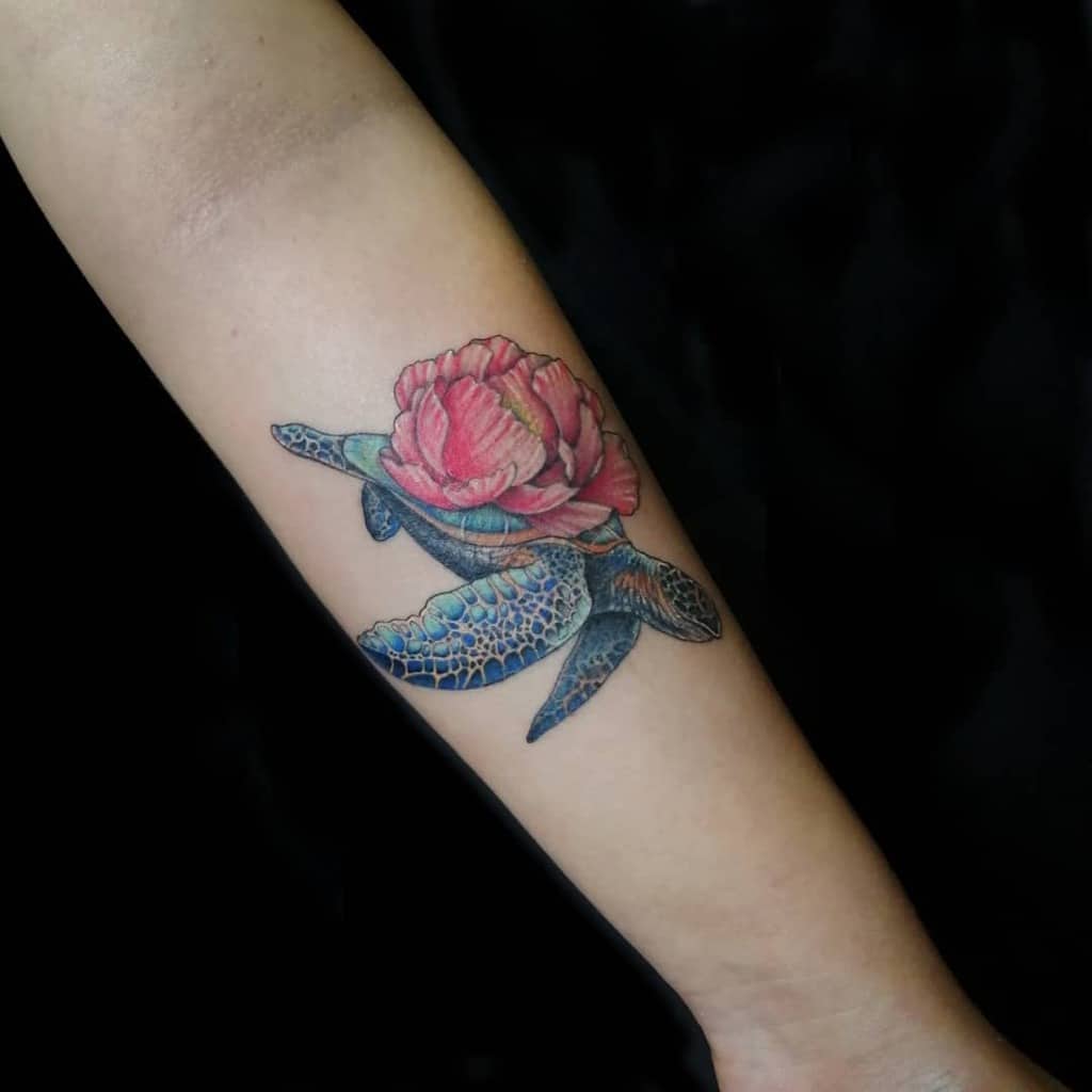 Tattoo of a turtle with a rose on its shell on a forearm