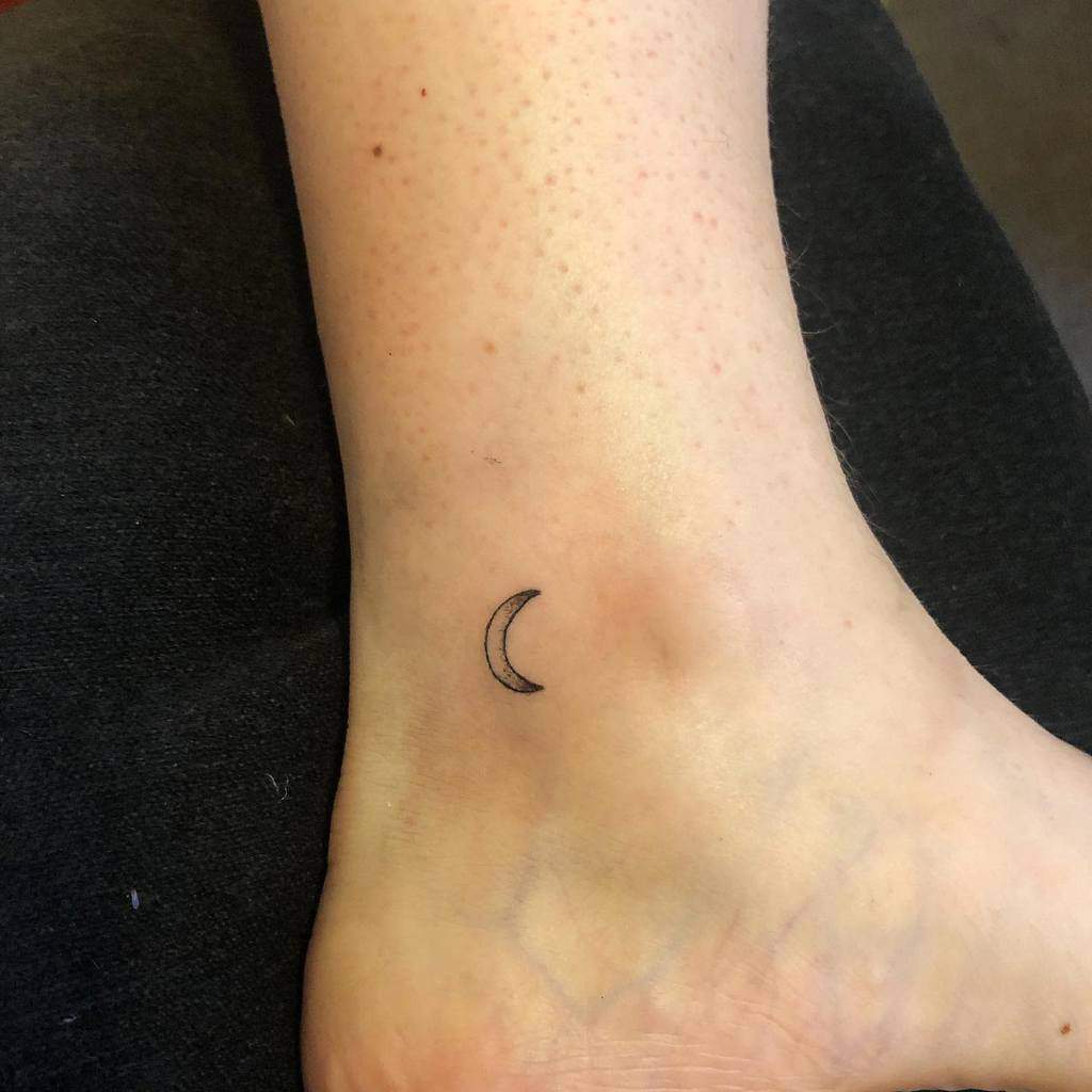Delicately etched small crescent moon tattoo on the ankle