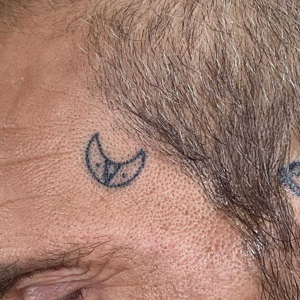 A small crescent moon tattoo near temple, adding celestial elegance