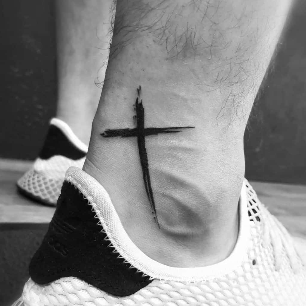 Black cross tattoo on an ankle