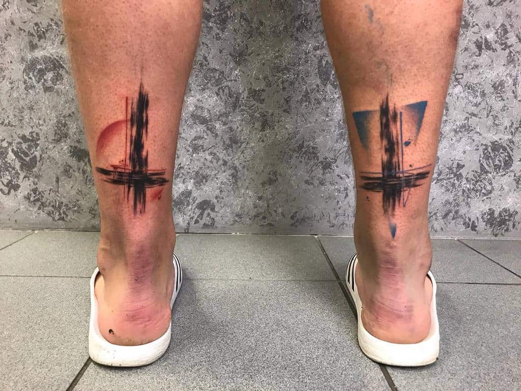 Abstract tattoos on calves with red and blue shapes