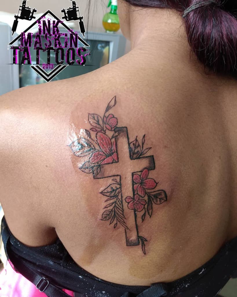 Tattoo of a cross with flowers on a shoulder