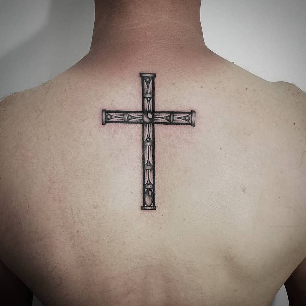 Tattoo of a cross with detailed shading on an upper back