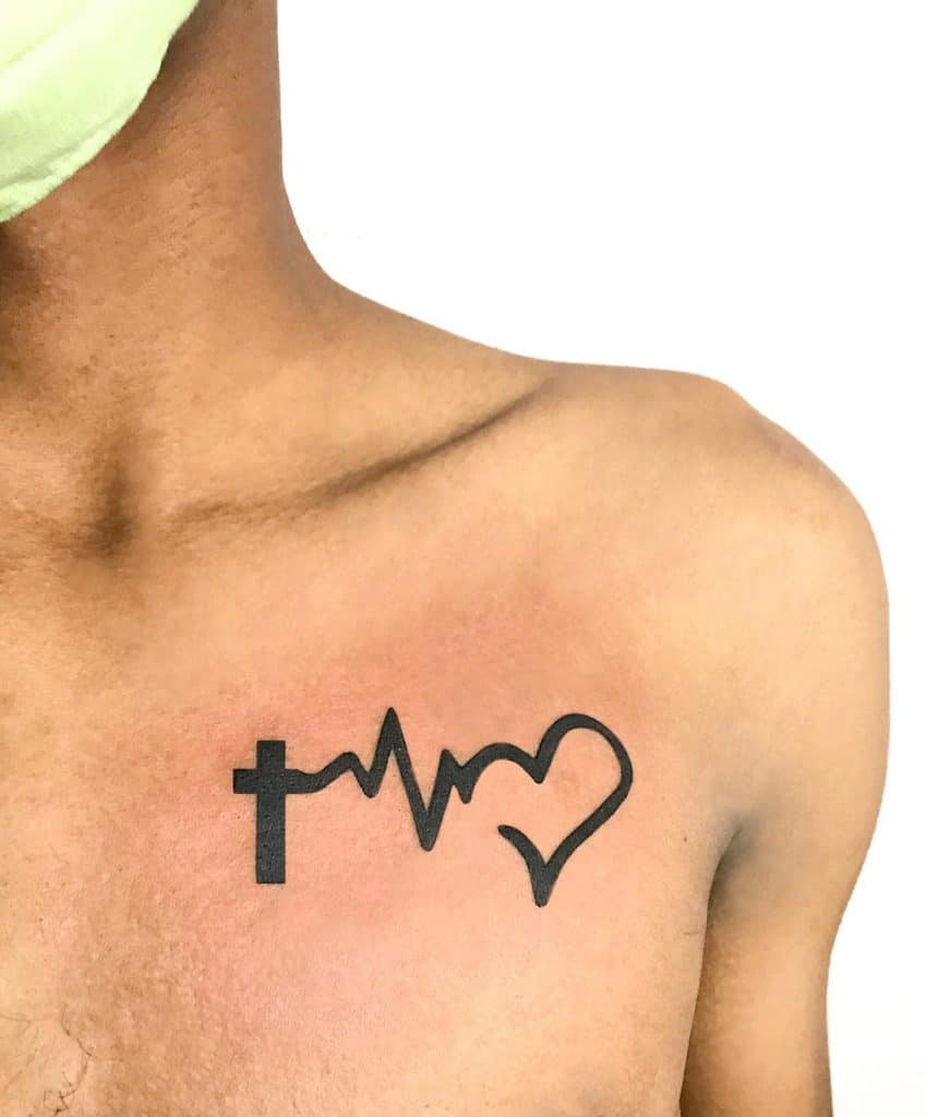A tattoo on a person's chest featuring a cross, heartbeat line, and heart shape