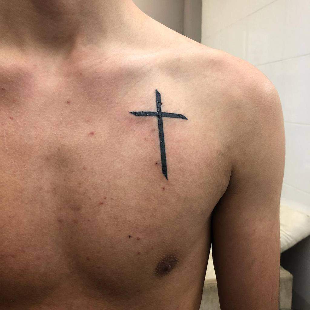 A person with a small black cross tattoo on their upper chest