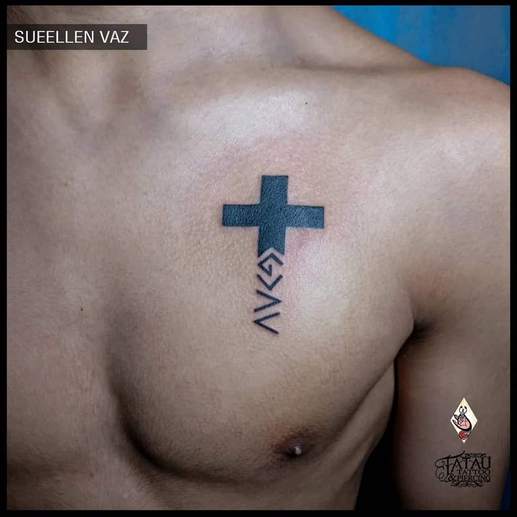 Bold black cross chest tattoo with geometric symbols below, creating a modern and meaningful design
