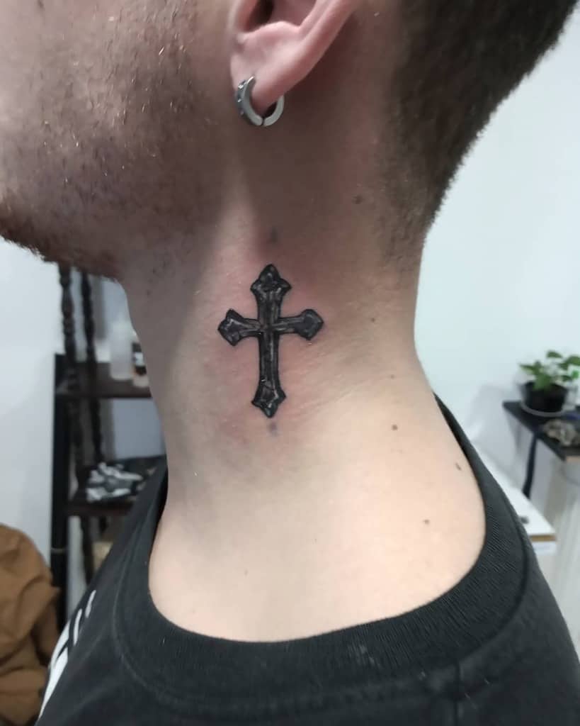 Detailed black cross tattoo on the side of the neck, featuring bold lines and intricate Gothic-inspired design