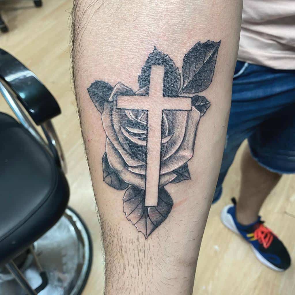 Tattoo of a cross and rose on a forearm