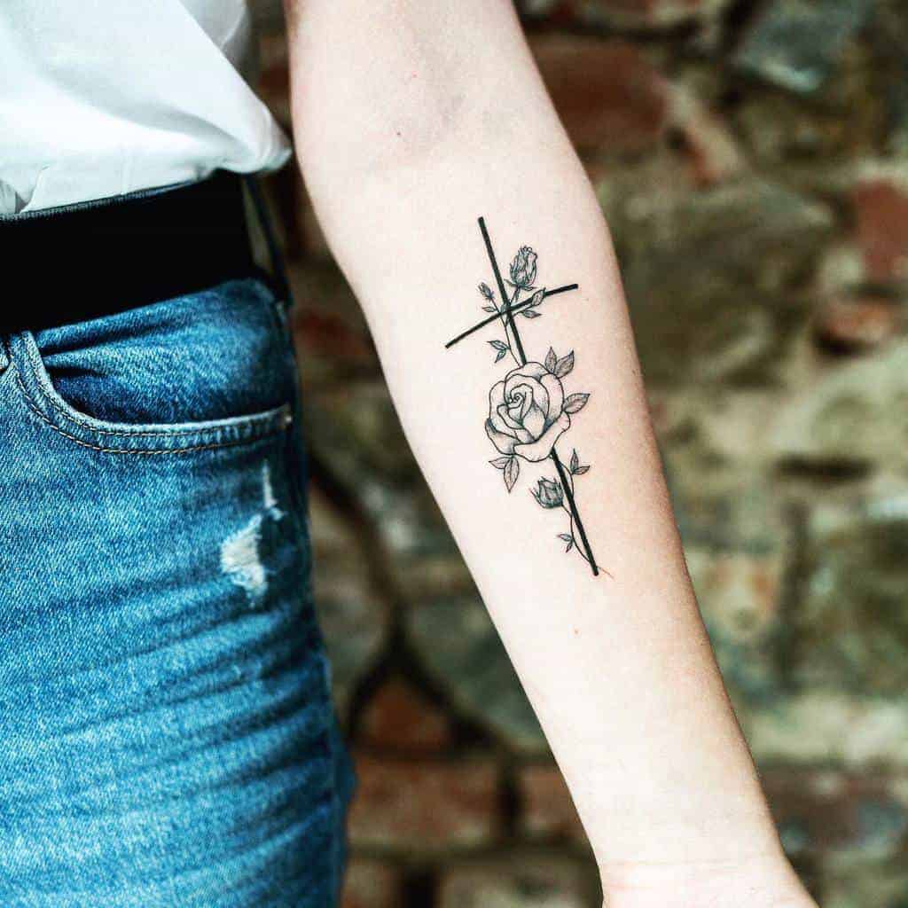 A tattoo of a rose wrapped around a cross on a person's forearm