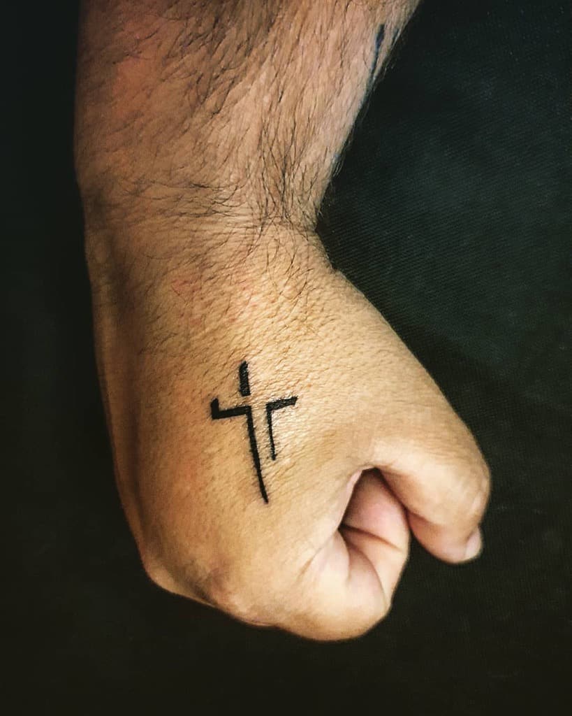 Hand with a black cross tattoo on the back