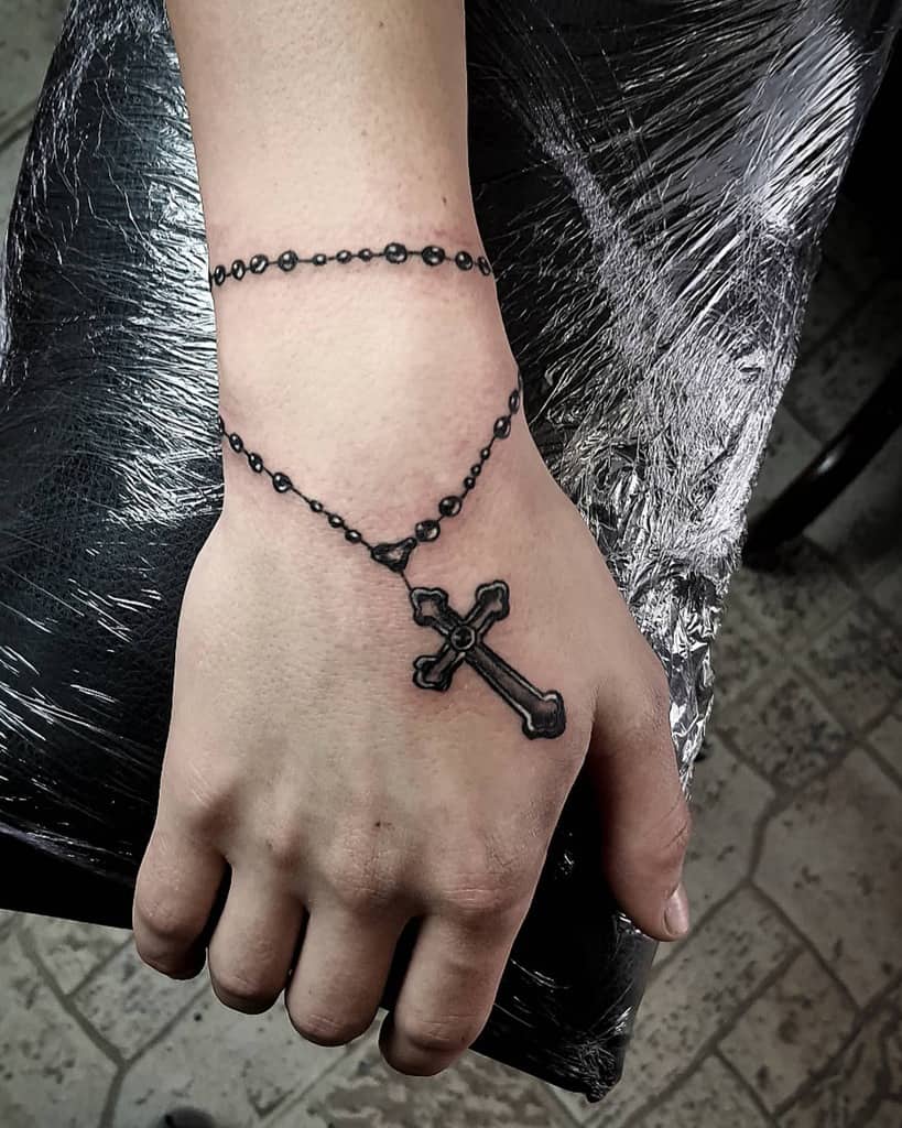 Hand with a tattoo of a chain and cross on top, creating a bracelet effect