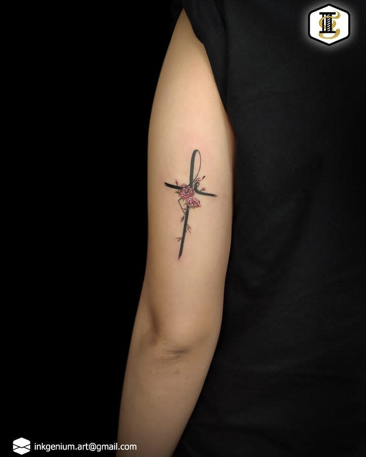 Arm with tattoo of a cross with a rose in the center