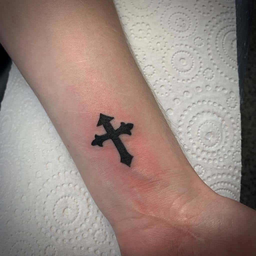 Black cross tattoo on an inner wrist