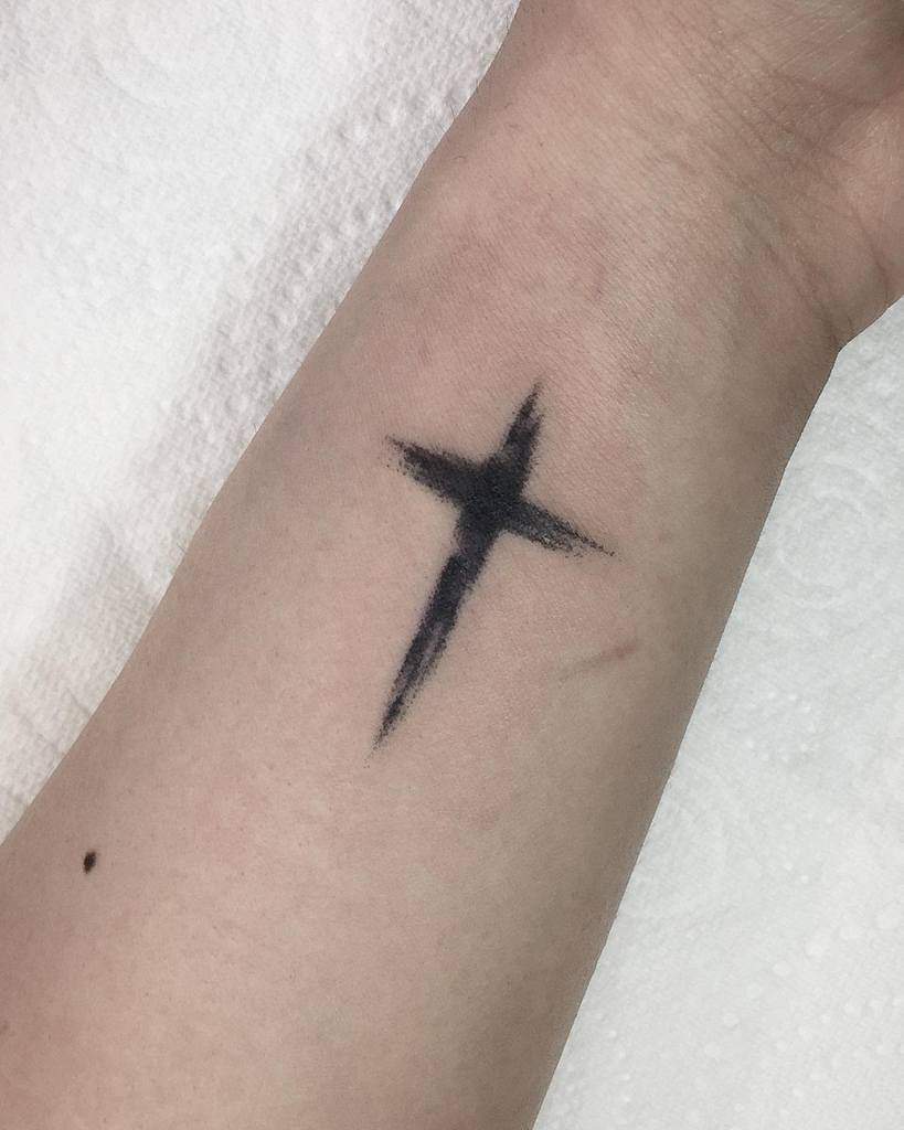 Tattoo of a black cross on a wrist