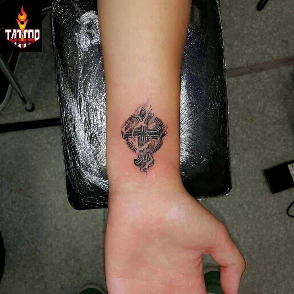 Intricate cross tattoo on the wrist with bold, textured detailing and a flame-like design for a unique and symbolic look