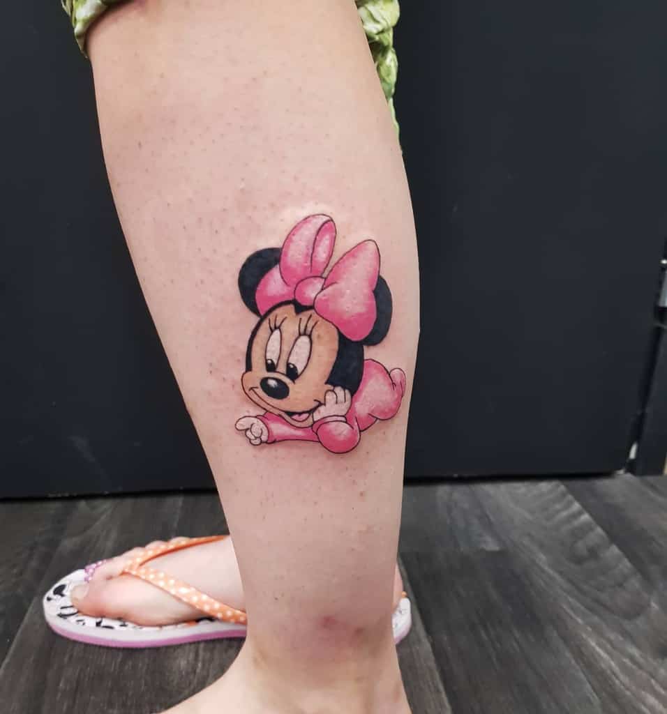 A playful and colorful tattoo of Minnie Mouse in her classic pink outfit and bow, designed with a cute, cartoonish style on the calf