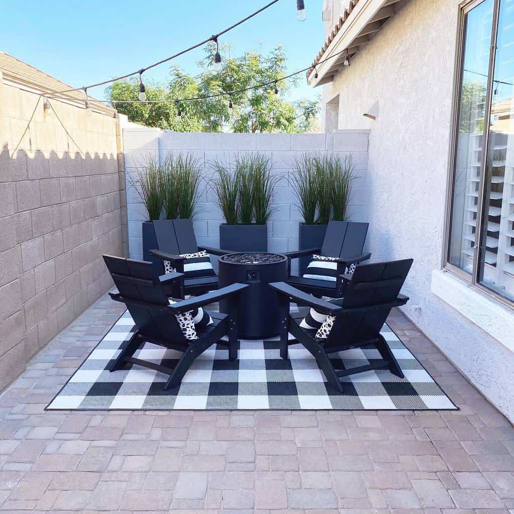 small backyard paved patio black deck chairs fire pit
