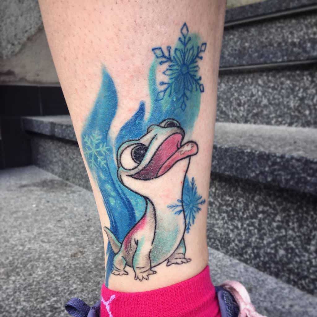 A vibrant tattoo of the character Bruni from Frozen 2, playfully surrounded by swirling blue ice and snowflakes on the ankle