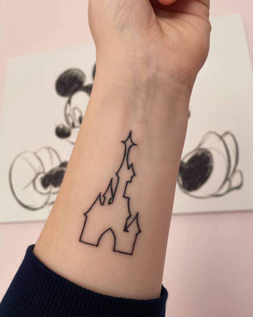 A minimalistic Disney castle tattoo with bold black lines, elegantly etched on the forearm